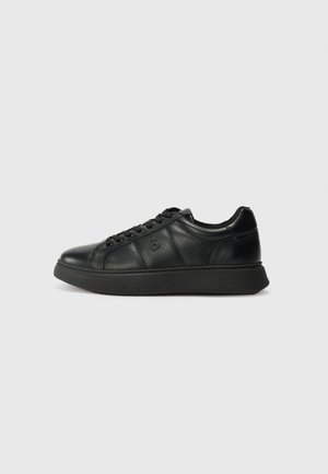 Black leather sneakers with a textured finish, featuring a rounded toe, lace-up design, and a thick rubber sole.