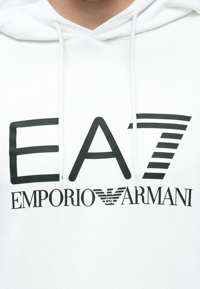Бял суитшърт с големи черни лога "EA7" и "EMPORIO ARMANI". Качулка с връзки и текстурирана материя с елегантен, неформален дизайн.