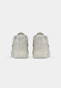 S ténis Nike Air em camurça cinza vistos de trás, com um acabamento texturizado, colarinho acolchoado e logótipo em relevo característico no calcanhar.