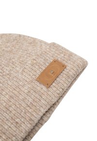 Cappello di maglia beige con un motivo testurizzato e un'etichetta in pelle marrone con un logo. Il tessuto sembra morbido e caldo.