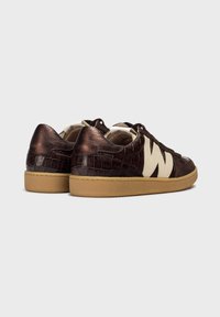 Brązowe skórzane sneakersy o teksturze krokodyla, z kremowymi akcentami, płaskimi sznurowadłami i gumową podeszwą. Posiadają charakterystyczne logo na boku.
