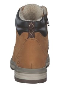 Botín de cuero marrón con un suave forro beige, cierre de cremallera y una franja texturizada marrón oscuro en la parte trasera que presenta un patrón de diamantes.