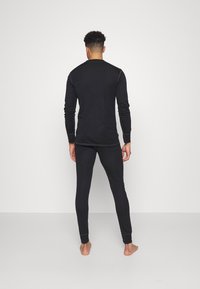 Maglietta nera a maniche lunghe e pantaloni aderenti realizzati in materiale morbido. Design semplice con dettagli di cucitura minimi e senza modelli visibili.