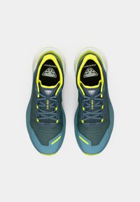 Αθλητικά παπούτσια σε τυρκουάζ και γκρι με κίτρινες λεπτομέρειες. Δίχτυ στην επάνω πλευρά, μαλακή επένδυση στον καρπό, υφή στη σόλα και ανακλαστικό λογότυπο στη γλώσσα.