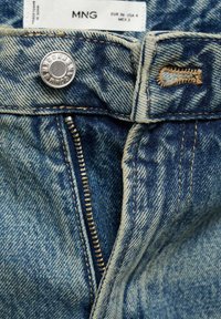 Jeans in denim azzurro chiaro con bottone e chiusura lampo in argento. Presentano cuciture a contrasto e un’etichetta con informazioni sulla taglia.