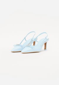 Svetlo modri lakirani slingback čevlji z usnjem, s koničastimi prstnimi deli, detajli v obliki mašne in srednje visokimi stiletto petami. Vidna podrobna šivanka.