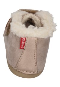 Scarpa scamosciata rosa chiaro con morbida fodera in pile crema, cinturino regolabile e etichetta con logo Kickers. Forma arrotondata e suola in gomma per una buona presa.