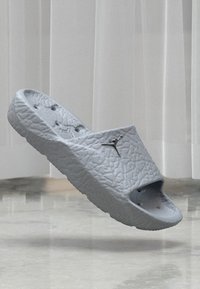 Sive moldirane klompe s teksturiranom površinom, otvorenim prstima i ventilacijskim otvorima, sa suptilnim logotipom.