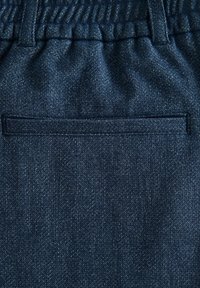 Tessuto denim di colore blu scuro con una texture morbida. Presenta una vita elastica e una semplice tasca cucita sul retro.