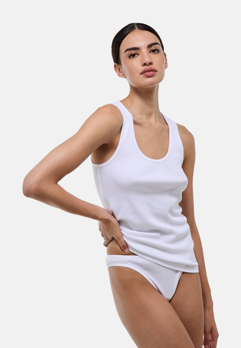 Débardeur blanc à texture côtelée avec bretelles larges, assorti d'un bas de bikini assorti. Design simple et ajusté, mettant en valeur un tissu lisse.