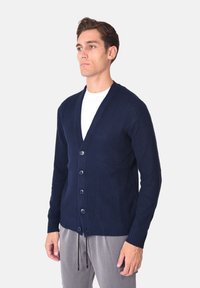Cardigan blu navy a coste con scollo a V, chiusura con bottoni e maniche lunghe, realizzato in materiale lavorato a maglia con trama.