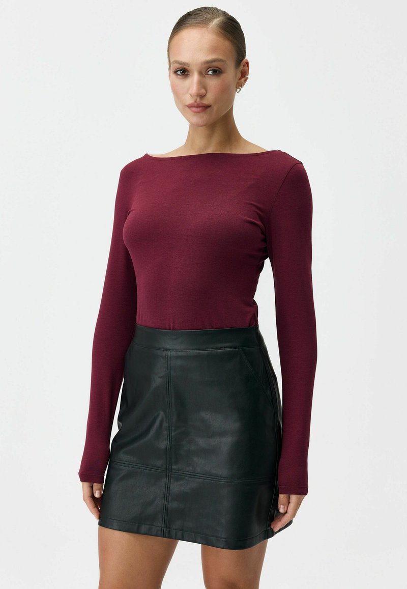 Bordowa bluzka z długim rękawem w połączeniu z czarną skórzaną spódnicą o dopasowanym kroju i widocznych szwach, tworząca elegancki, nowoczesny wygląd.