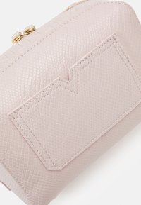 Pouch in pelle texturizzata rosa con un accento geometrico, hardware della cerniera dorata e dettagli di cucitura visibili. Forma compatta e rettangolare.