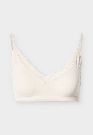 Cremefarvet bralette med blonderkant, justerbare stropper og blødt, glat stof. Har en v-udskæring og sømløst design for komfort.