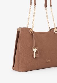 Borsa di colore marrone con texture, manici a catena dorati, charm a forma di cuore dorato e piccolo logo "MIRIADE" dorato sul davanti.