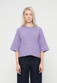 Pull court violet en maille douce avec manches larges et encolure ronde, associé à un jean en denim foncé.