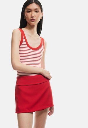 Rotes geripptes Tanktop mit weißen und roten Streifen, kombiniert mit einem figurbetonten roten Minirock aus glattem Material und mit gefaltetem Bund.