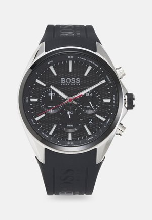 Black Hugo Boss chronograph watch with silver markers, tachymeter scale, three subdials, date window, and black rubber strap.