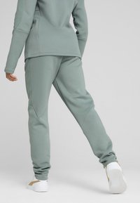 Survêtement de sport vert clair avec manches longues et pantalon fuselé, fabriqué dans un matériau doux. Présente des accents côtelés et une texture lisse.