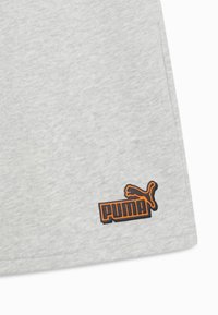 Tela gris claro con un pequeño parche del logo de Puma en naranja y negro en el borde inferior.