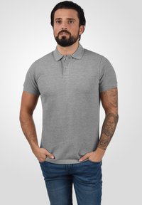 Grå bomulds polo skjorte med krave, tre knapper, korte ærmer og en tætsiddende pasform, bæres med blå denim jeans.