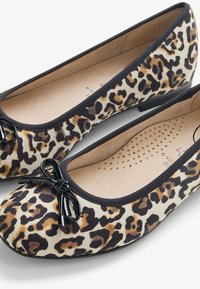 Ballerines pour femmes en tissu imprimé léopard, bordure noire et petit nœud noir sur l’avant, avec semelles intérieures rembourrées et talons bas.
