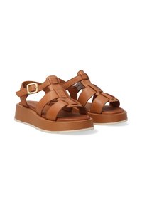 Braune Ledersandalen mit einer Plattformsohle, ausgestattet mit überkreuzten Riemen, einem seitlichen Schnallenverschluss und einem offenen Zehenbereich. Strukturiertes Finish.