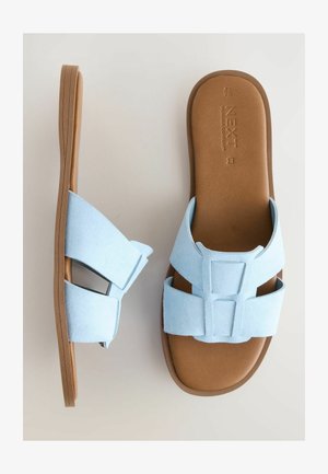 Sandales en suède bleu clair avec deux larges brides, design ouvert et semelle texturée marron. Présente un accent géométrique sur les brides.