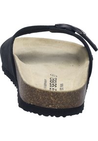 Chancla negra con plantilla de corcho, suela interior texturizada en beige y correa ajustable con hebilla plateada. Suela plana de goma.