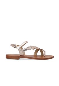 Flad sandal med metallisk rosaguldremme, fletdesign, justerbar ankelspænde og en lysebrunt træsål. Glat tekstur.