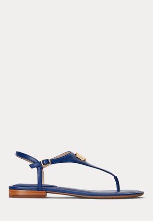 Marineblaue flache Ledersandale mit dünnem T-Riemen, kleiner goldener Schnalle und niedrigem Holzabsatz.