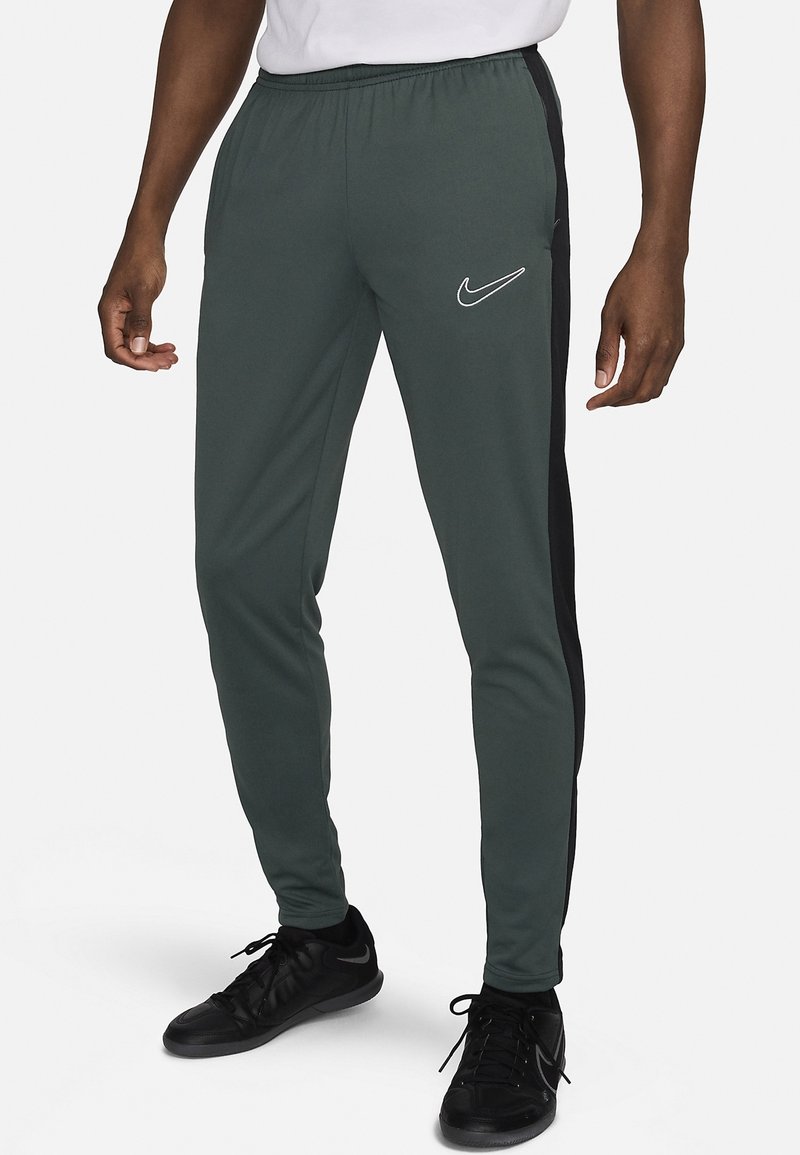 Heren sportbroeken in donkergroen met zwarte zijpanelen. Voorzien van een elastische tailleband en een wit Nike-logo op de dij.