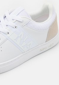 Sneaker bianche con tomaia in pelle liscia, inserti in rete e un sottile tallone in suede beige. Presentano una scritta in rilievo e una suola in gomma.