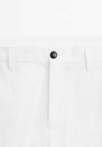 Weiße Leinenhose mit flachem Vorderteil, einem schwarzen Knopfverschluss und subtiler Textur. Enthält Gürtelschlaufen und genähte Taschen.