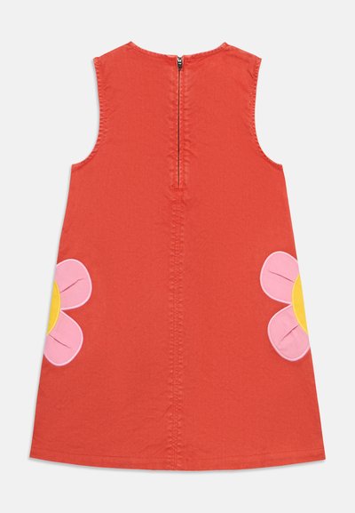 Vestido rojo sin mangas con cremallera trasera, decorado con grandes parches de flores rosas y amarillas a cada lado cerca del dobladillo.