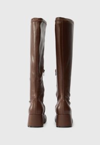 Brown leather knee-high boots with a smooth texture, rounded square toe, and block heel; features a zipper on the side for closure.