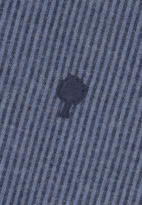 Blauw gestreepte stof met afwisselend lichte en donkere tinten, voorzien van een klein, geborduurd boompje logo in marineblauw. Zachte textuur, gemiddelde zwaarte.