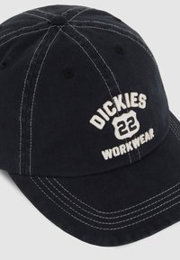Svart bomullsmisserie med vit broderad "DICKIES 22 WORKWEAR" logga, har kontrastsömmar och en krökt skärm.