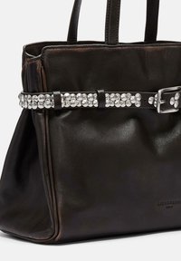 Czarna torba typu tote ze skóry o fakturowanej powierzchni, dwoma uchwytami u góry oraz ozdobnym pasem z metalowymi ćwiekami w srebrnym odcieniu z metalową klamrą.