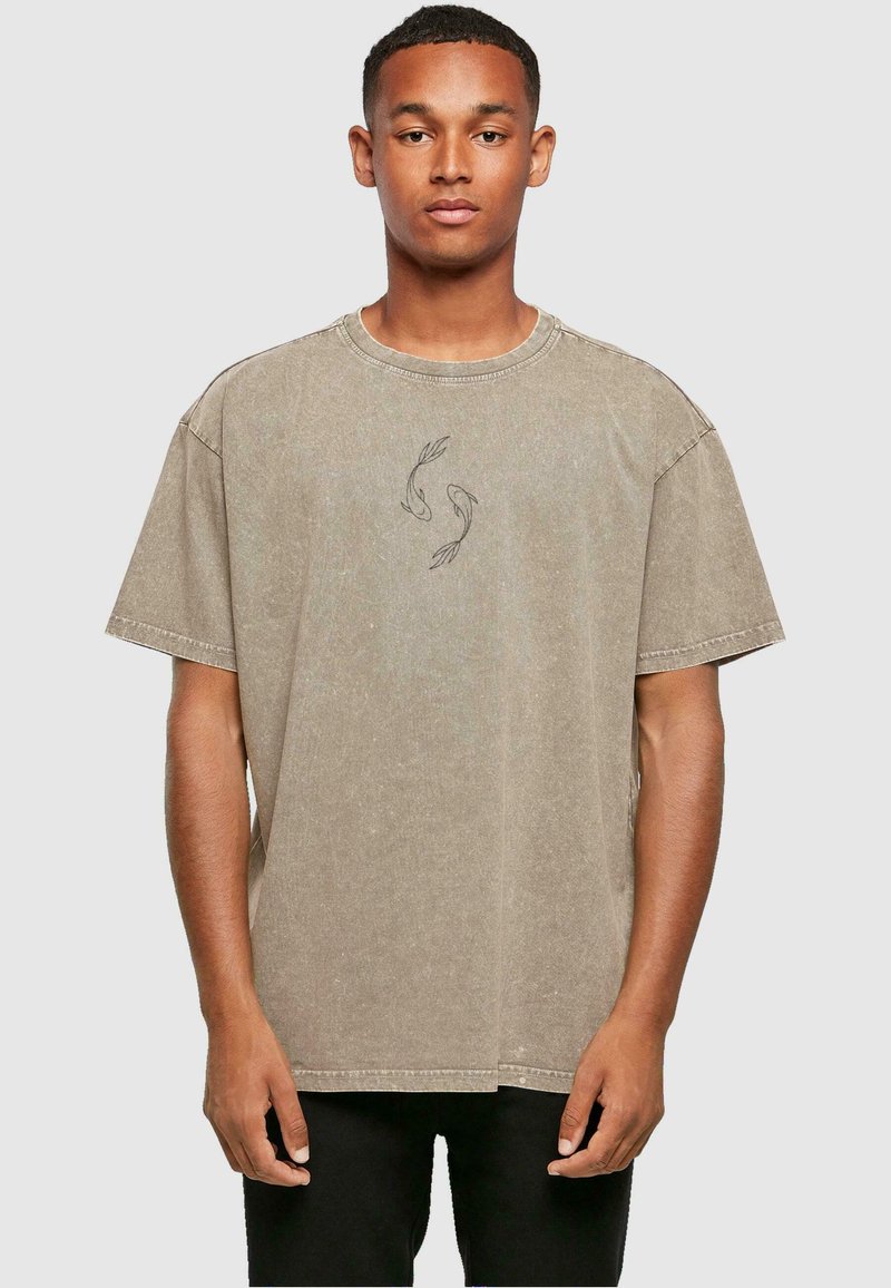Kortærmet, oversized, beige bomulds T-shirt med rund halsudskæring og grå fiskegrafik på brystet. Diskret vasket struktur.