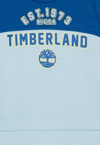 Felpa blu e azzurra con la scritta e il logo "TIMBERLAND", scollo rotondo e polsini a costine all'orlo e alle aperture delle maniche.