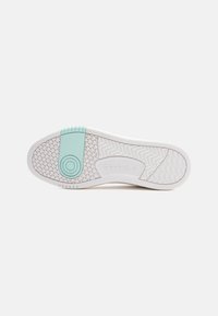 Sola do sapato Reebok com uma base branca, padrões texturizados e uma tira de destaque em verde menta perto do calcanhar, com um detalhe de marcação circular.