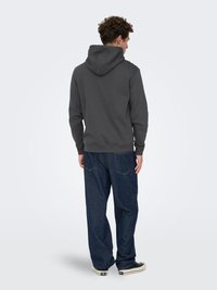 Gray hooded sweatshirt with a relaxed fit, paired with dark denim jeans. The sweatshirt has a smooth texture and ribbed cuffs.