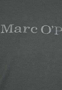 T-shirt grigio scuro con testo metallico argento che legge "Marc O’P" in un font casual e arrotondato. Tessuto morbido e liscio con una trama semplice.