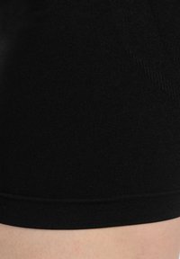 Zwarte strakke shorts met een gladde, geribbelde textuur en een brede elastische tailleband. De stof lijkt zacht en rekbaar. Geen zichtbare patronen of accenten.