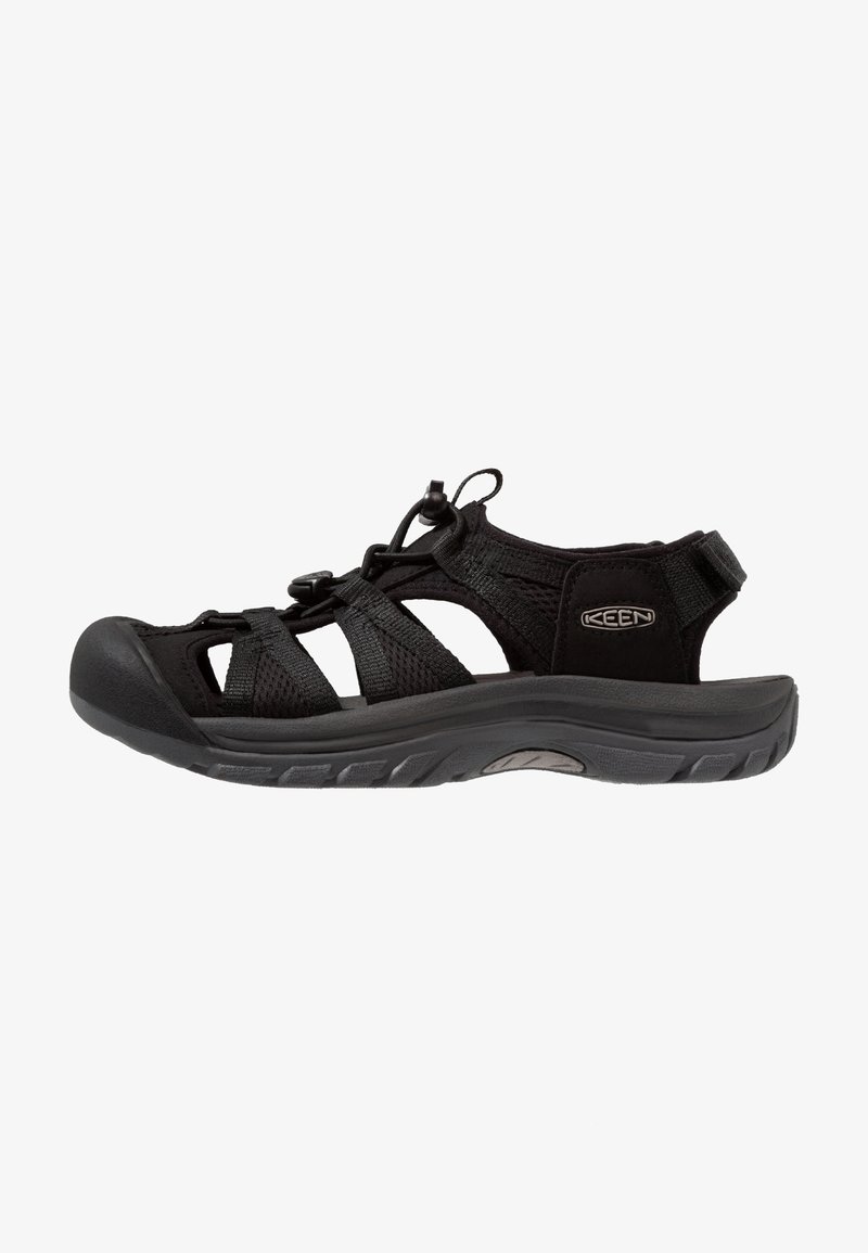 Black sandal with mesh upper, elastic laces, and rubber sole. Features adjustable heel strap and cut-out design for breathability.