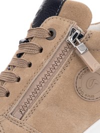 Beiger Wildlederschuh mit dicken Schnürsenkeln, seitlichem Reißverschluss, gesteppten Details und einem runden Logoanhänger mit der Aufschrift "seit 1949".