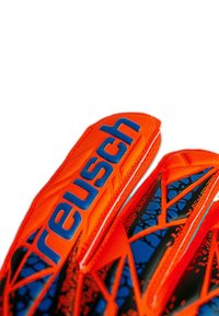 Gants de gardien Reusch en matériau orange vif avec des accents bleus. Le design inclut des motifs texturés et une structure de doigts distinctive.