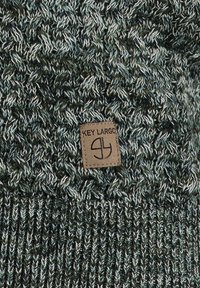 Cappello lavorato a maglia in filato verde scuro e azzurro chiaro caratterizzato da un motivo testurizzato e da una patch in pelle marrone con la scritta "KEY LARGO" incisa.