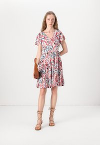 Floral dress with a V-neck, short puff sleeves, and a cinched waist. Features a pink, blue, and red paisley pattern. Beige strappy sandals.